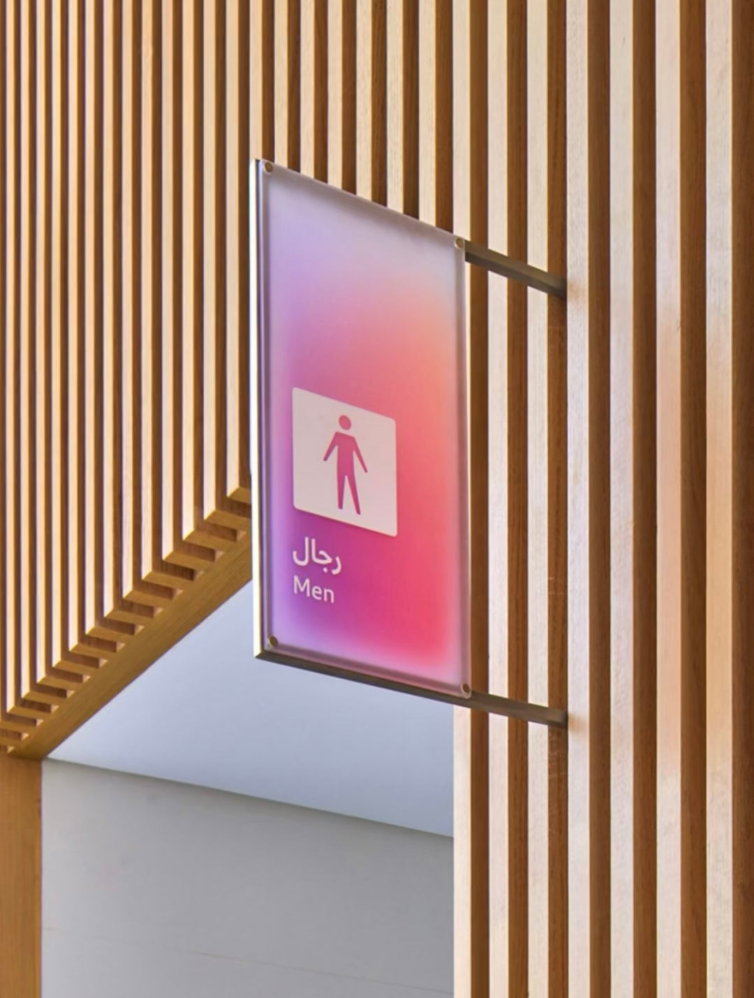 Wall-mounted acrylic gradient wayfinding sign with LED lighting integrated into modern architectural interiors