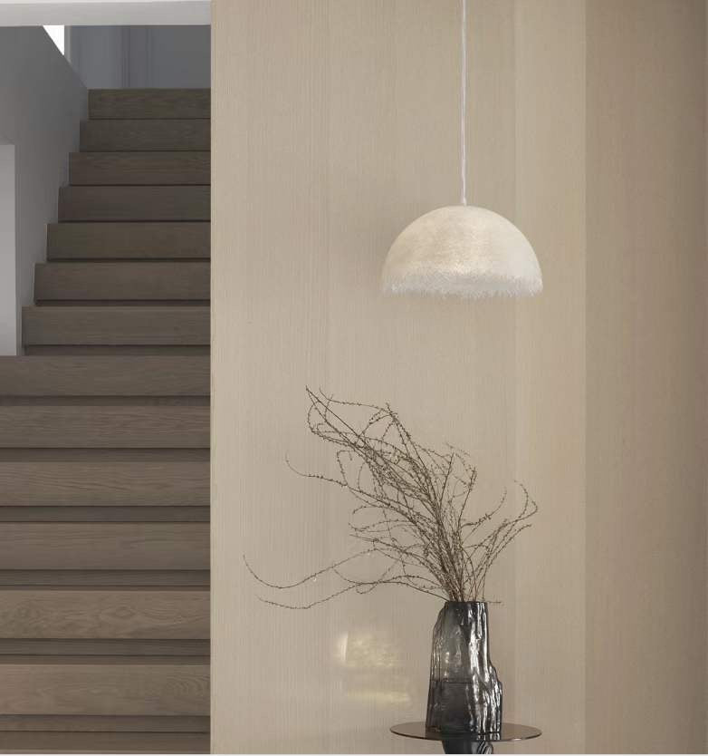 a softly diffused pendant light suspended in a stair void, adding warm ambient illumination and visual softness to the vertical space