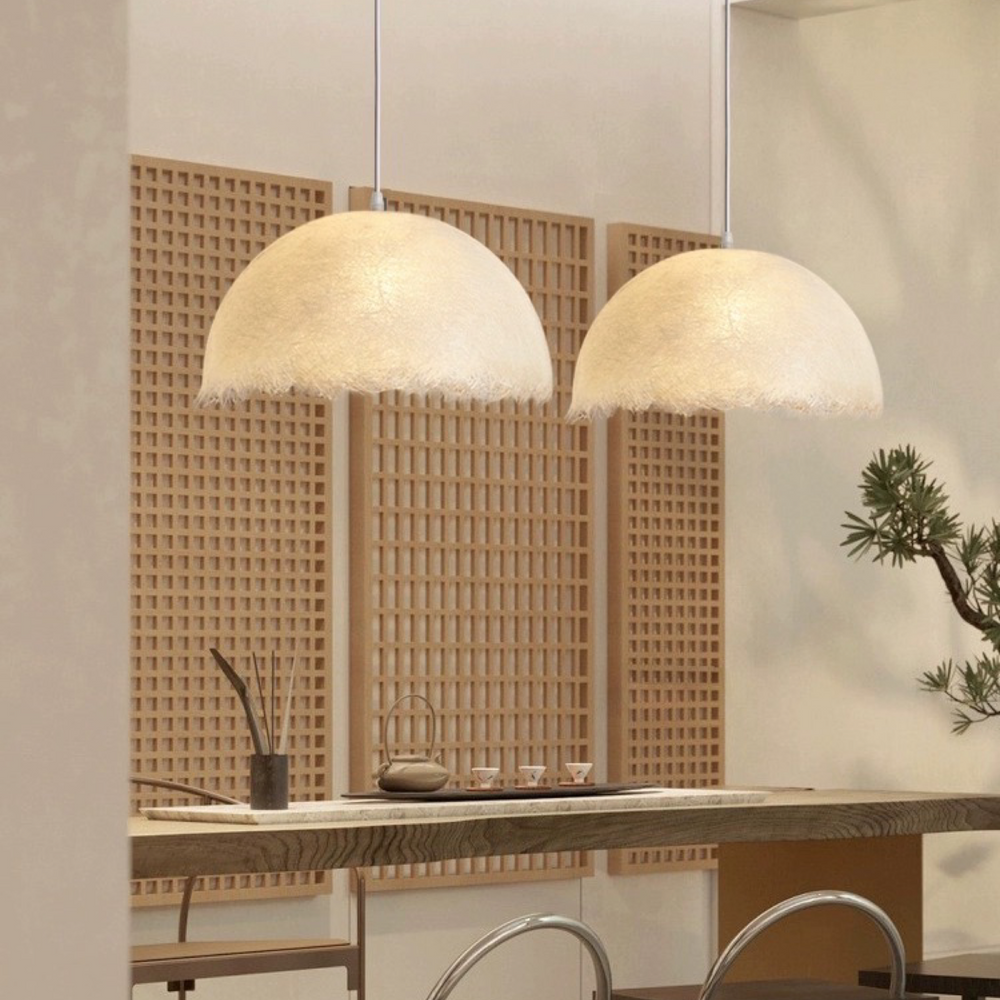 two ambient pendant lights hanging above a kitchen dining area, providing gentle diffused light and a relaxed spatial mood