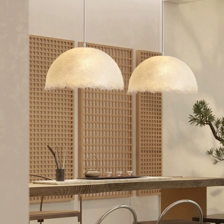 two ambient pendant lights hanging above a kitchen dining area, providing gentle diffused light and a relaxed spatial mood