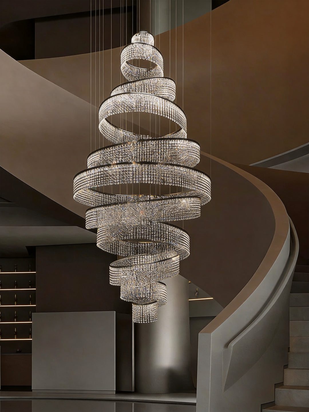 Bespoke spiral crystal ring chandelier close-up view in a double-height staircase void with warm bronze interior, Luminous Eleven Bespoke Lighting by Lucretia