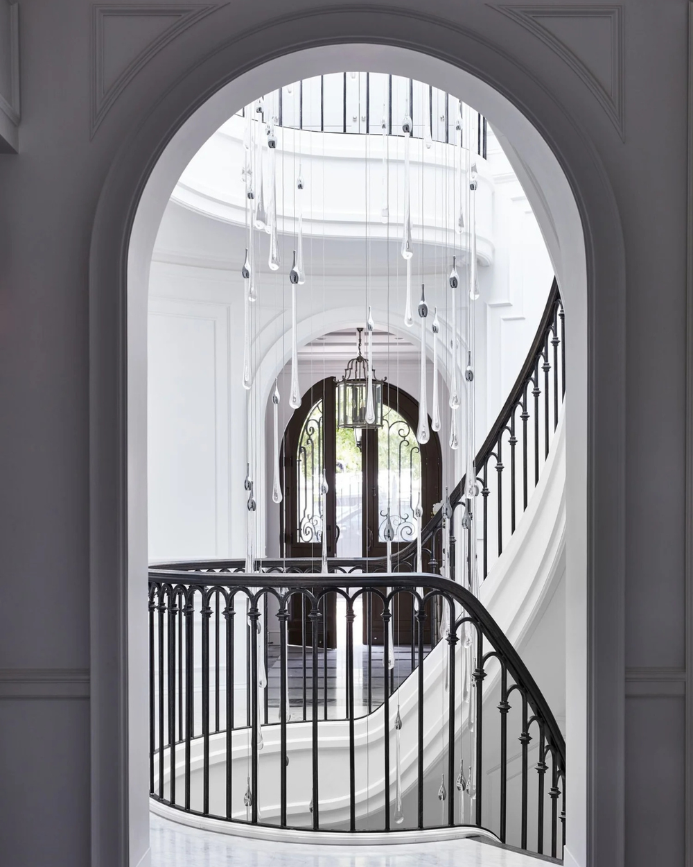 Bijou Custom Void Pendant Light of suspended glass raindrops descending through a stairwell above a grand residential entrance