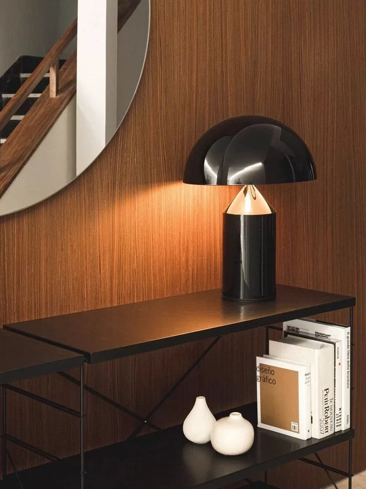 Black dome table lamp providing warm ambient glow in a modern bedroom setting, suitable for desks, consoles and nightstands.