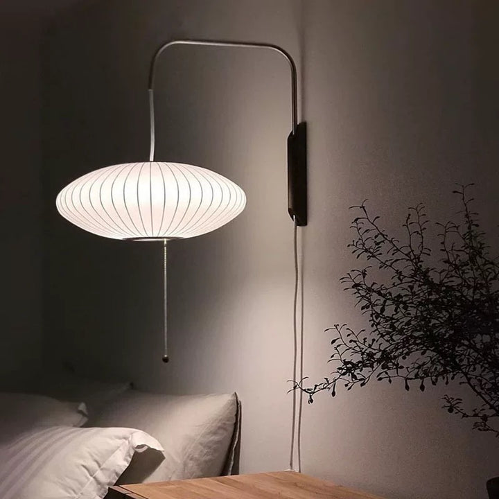 white cocoon saucer wall lamp glowing softly beside bed plug in design ideal for bedrooms hallways reading corners and australian ambient interior lighting