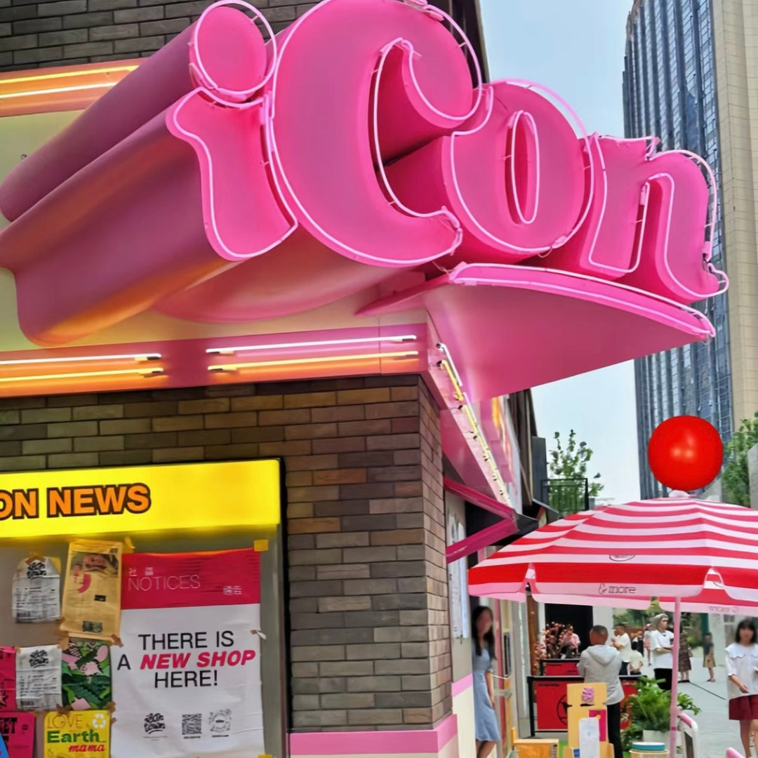 Custom 3D corner neon letter signage wrapping a retail storefront corner with bold pink neon illumination.
