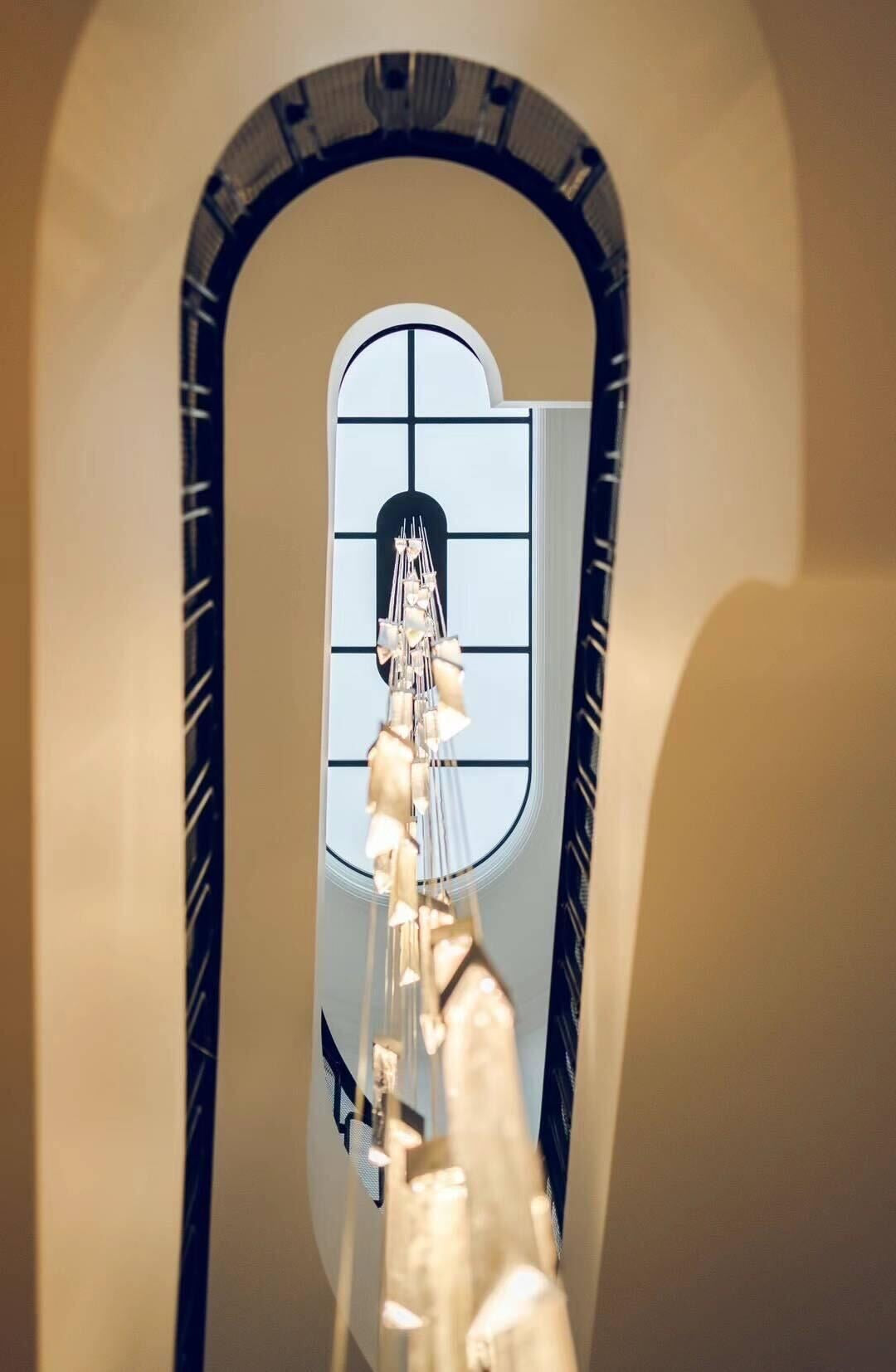 Architectural double-height staircase chandelier with vertical suspended Swedish glass pendants viewed from below