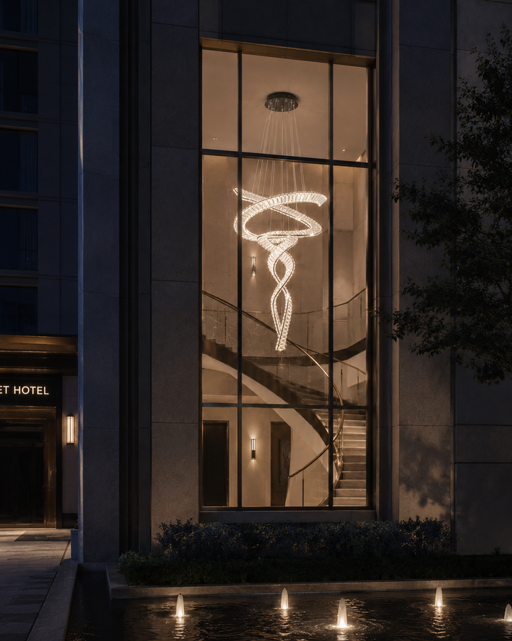 Dual spiral crystal chandelier visible through hotel glass facade at night with water feature in foreground, Pharaoh Tour Double 1200 Chandelier by Lucretia