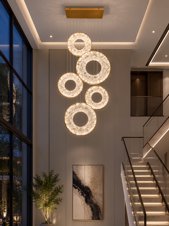 Galactic Halo Pendant Light with five textured crystal rings suspended in a double-height residential void beside a staircase