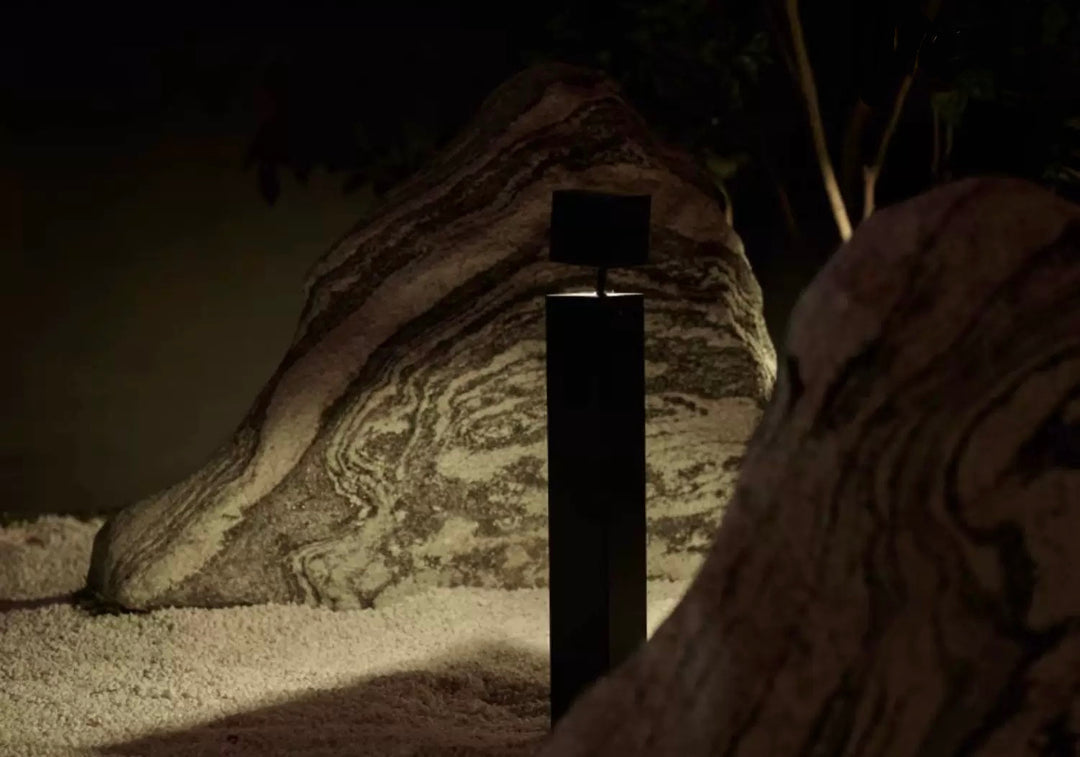 LED garden bollard light illuminating landscape rock feature at night