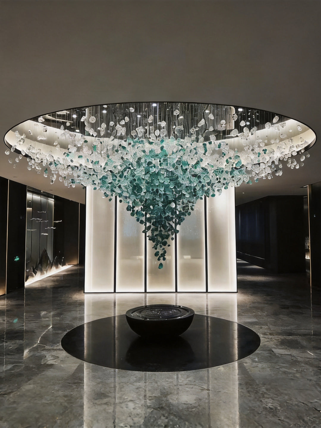 Green and clear hand-blown glass stone sculpture chandelier suspended beneath a circular ceiling in a luxury hotel lobby with black marble flooring, StoneLuxe Sculpture by Lucretia