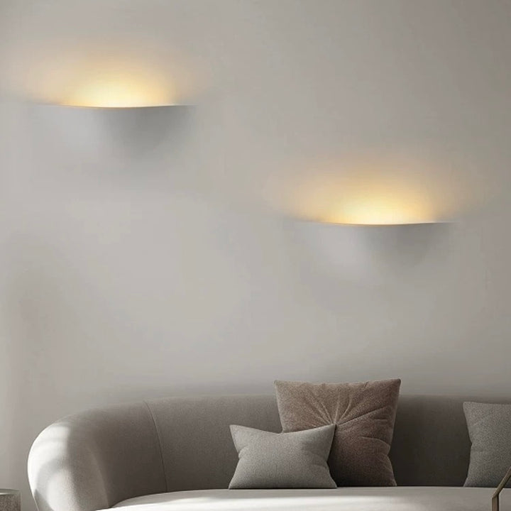 sunrise gypsum LED wall light creating warm ambient wall lighting above a modern living room sofa