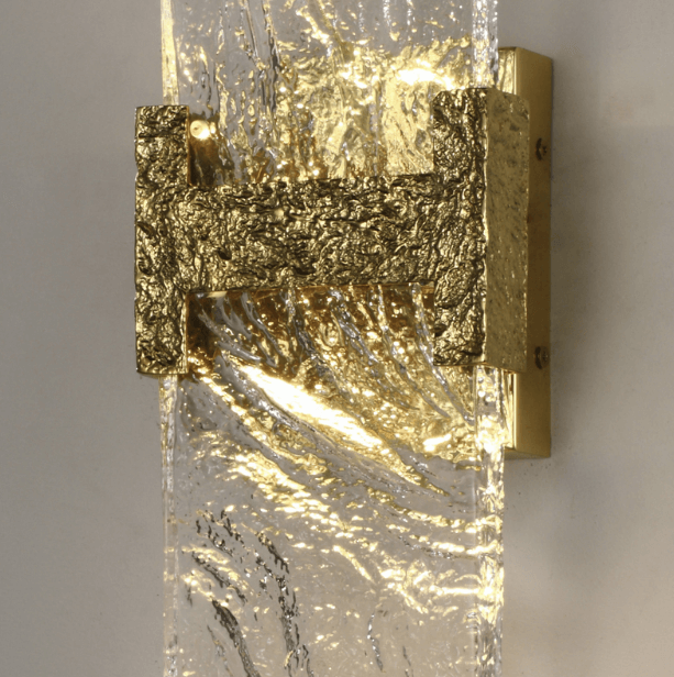 close-up of incu wall lamp showing carved brass fixture and textured glowing glass panel providing soft ambient led illumination for interior spaces