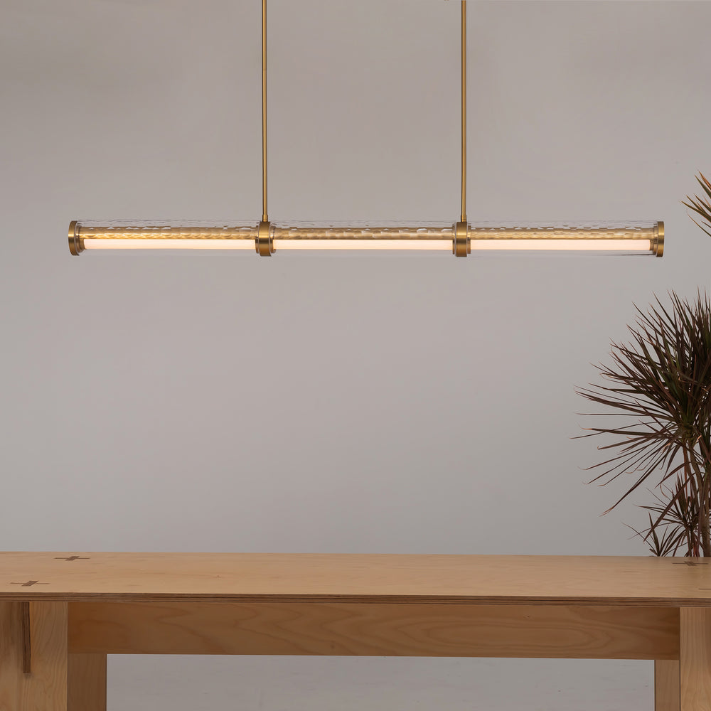 Linear pendant light above dining table with textured crystal glass