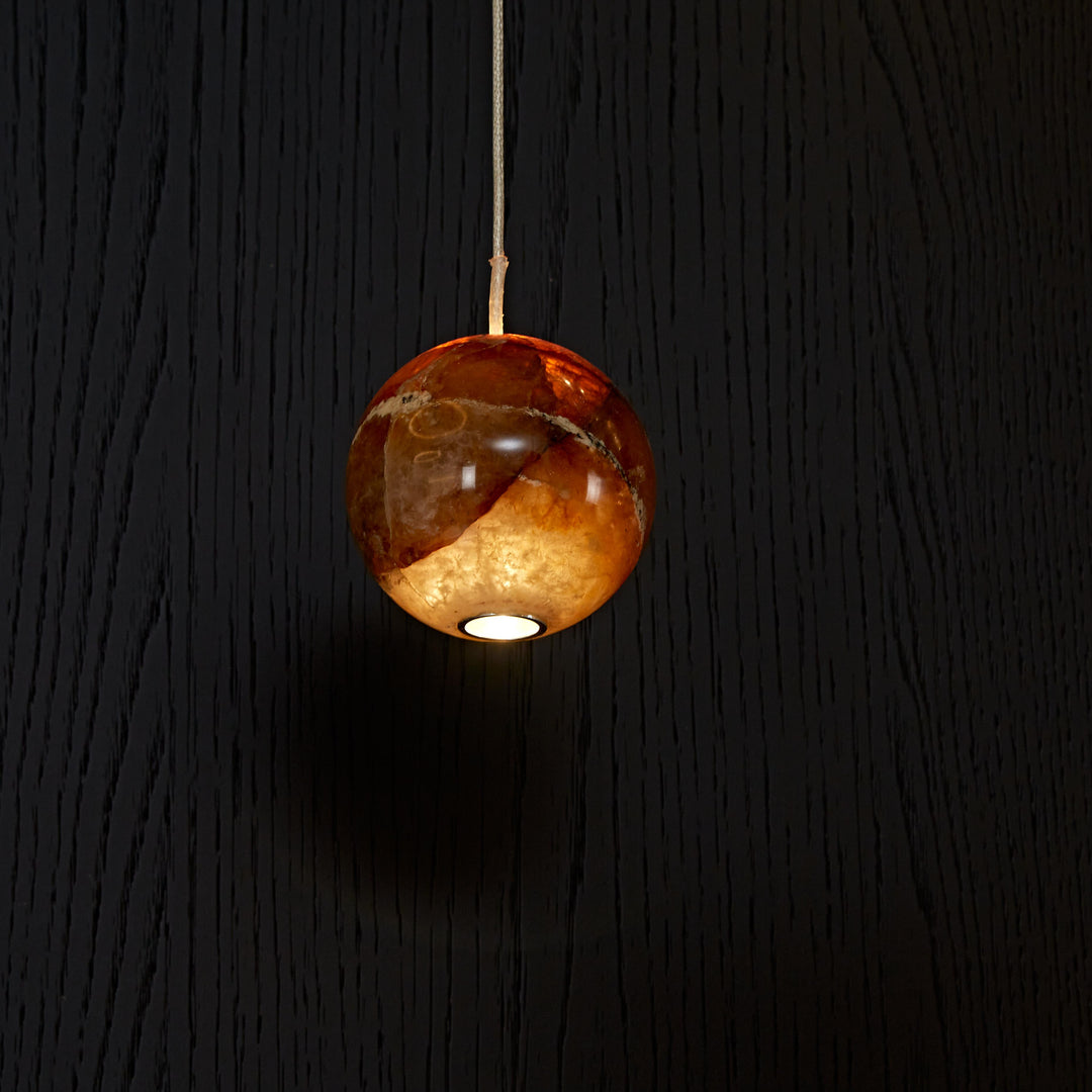 Close-up of a handcrafted Brazilian natural agate pendant light showcasing unique crystal patterns and warm LED illumination.