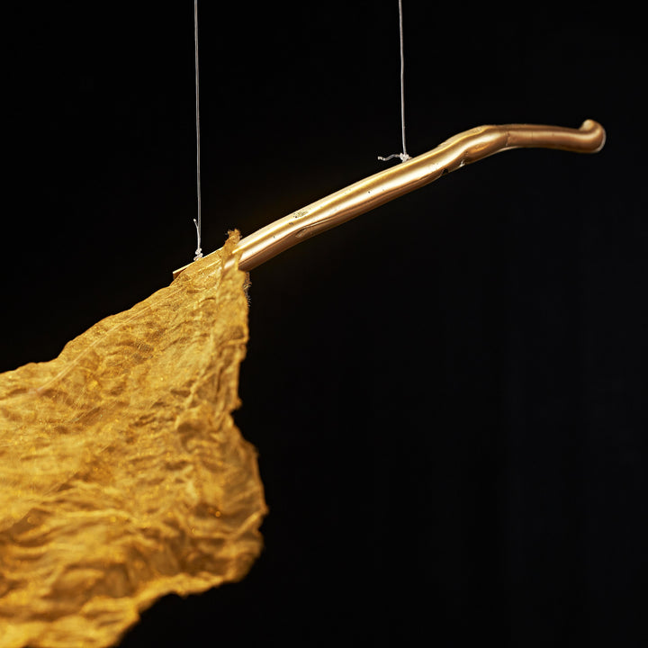Close-up of the Gilded Leaf Pendant Light showing a sculptural gold branch and handcrafted metallic woven leaf detail.