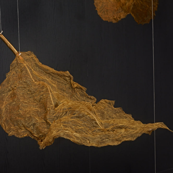 Detailed view of the handcrafted metallic woven leaf sculpture from the Gilded Leaf Pendant Light collection.