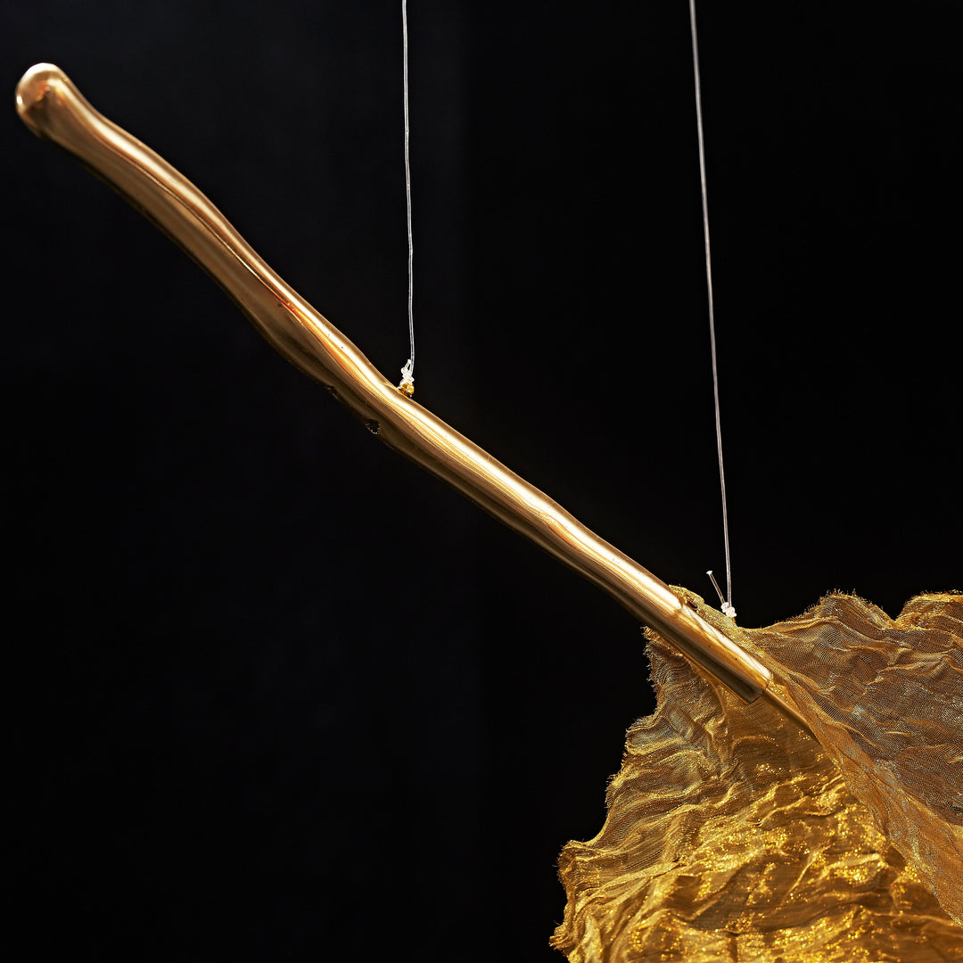 Close-up of the sculptural branch and handcrafted metallic leaf of the Gilded Leaf Pendant Light.