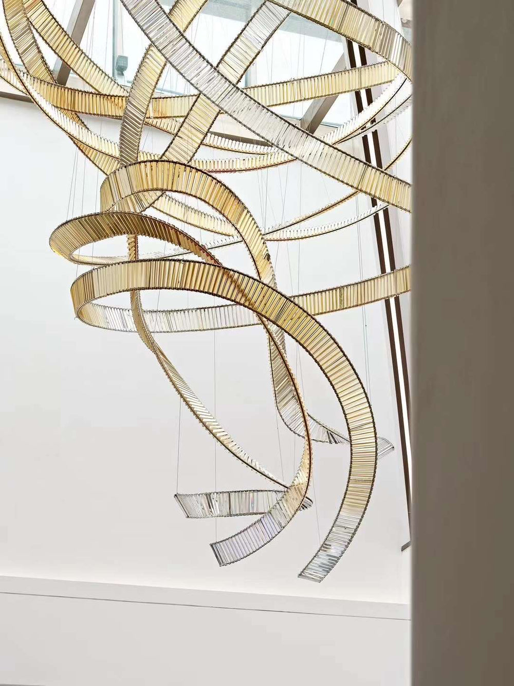 Lucretia Lighting Infinity bespoke lighting installed as a sculptural crystal feature in an architectural void, highlighting custom flowing design
