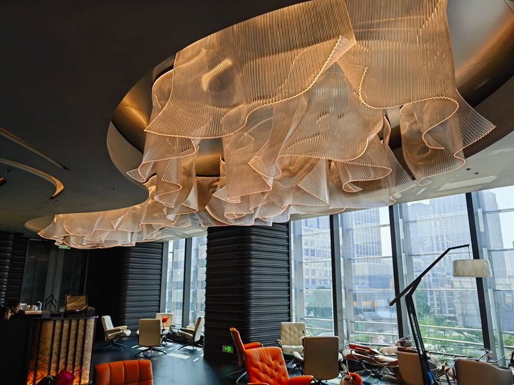 Lucretia Lighting infinity waves bespoke pendant light creating a sculptural luxury custom lighting feature across a hotel lobby with flowing wave-like design