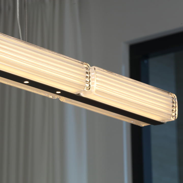 Striato 10 LED linear pendant close up highlighting elongated form and soft diffused light for architectural kitchen and dining lighting