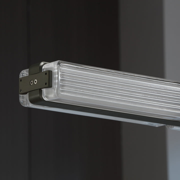 detail view of Striato 10 linear pendant with gunmetal finished frame and ribbed glass creating refined modern designer lighting