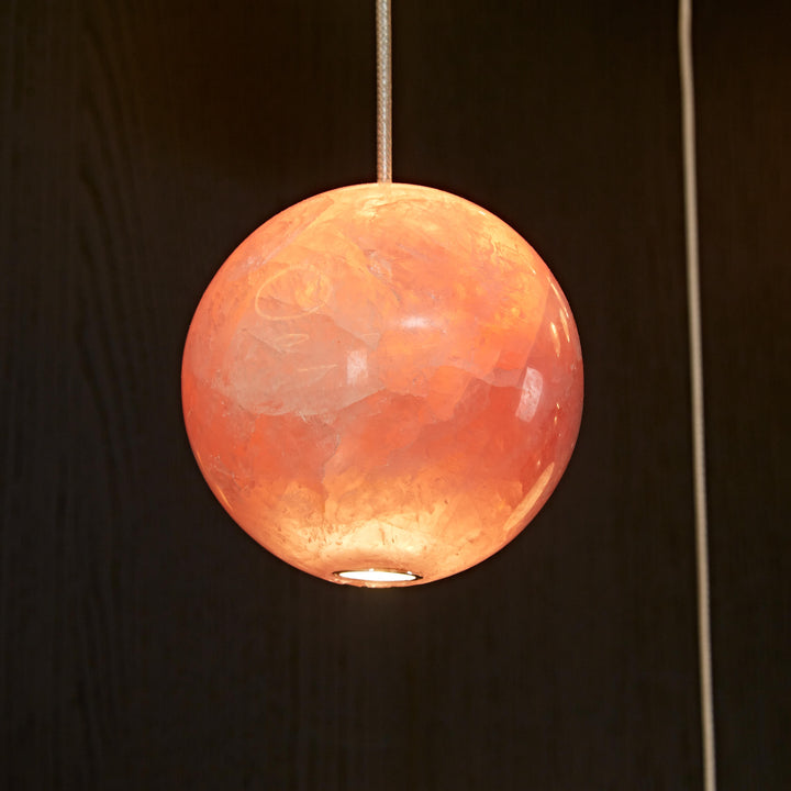 Pink natural agate pendant light with translucent stone illuminated by integrated LED lighting.