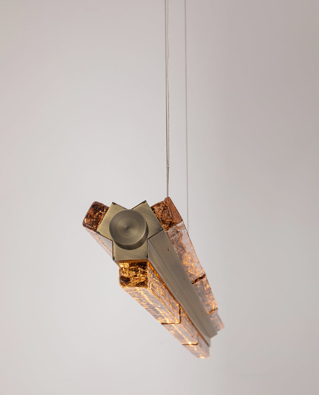 Antique brass linear pendant light with handcrafted amber textured glass.