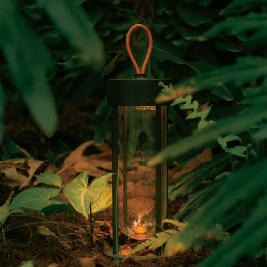 MK2 rechargeable LED lantern glowing softly in an outdoor forest setting.