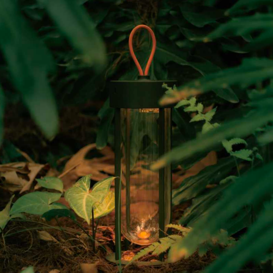 MK2 rechargeable LED lantern glowing softly in an outdoor forest setting.