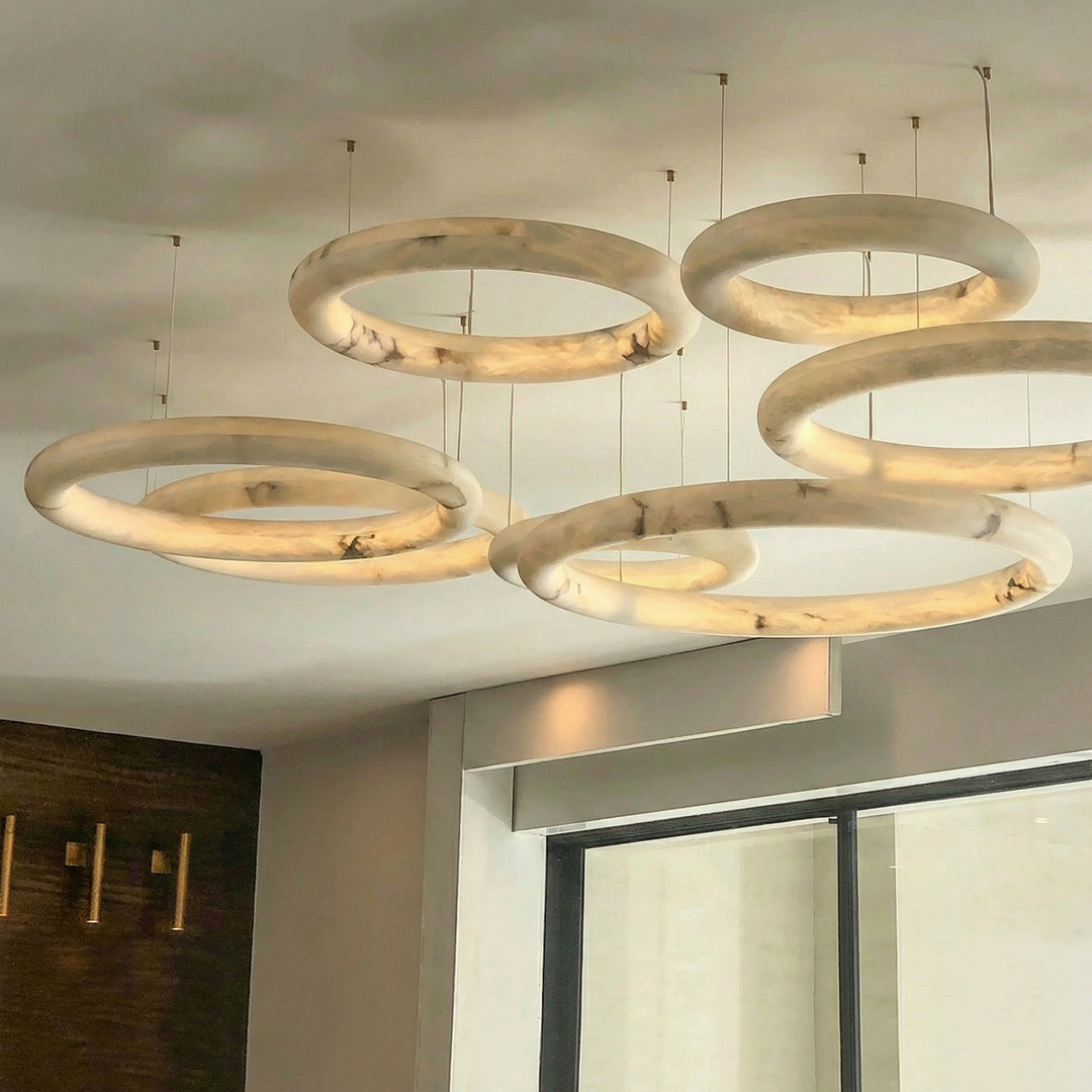 Multi ring alabaster chandelier installation in staircase void with architectural lighting design – Aurelia
