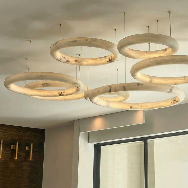 Multi ring alabaster chandelier installation in staircase void with architectural lighting design – Aurelia