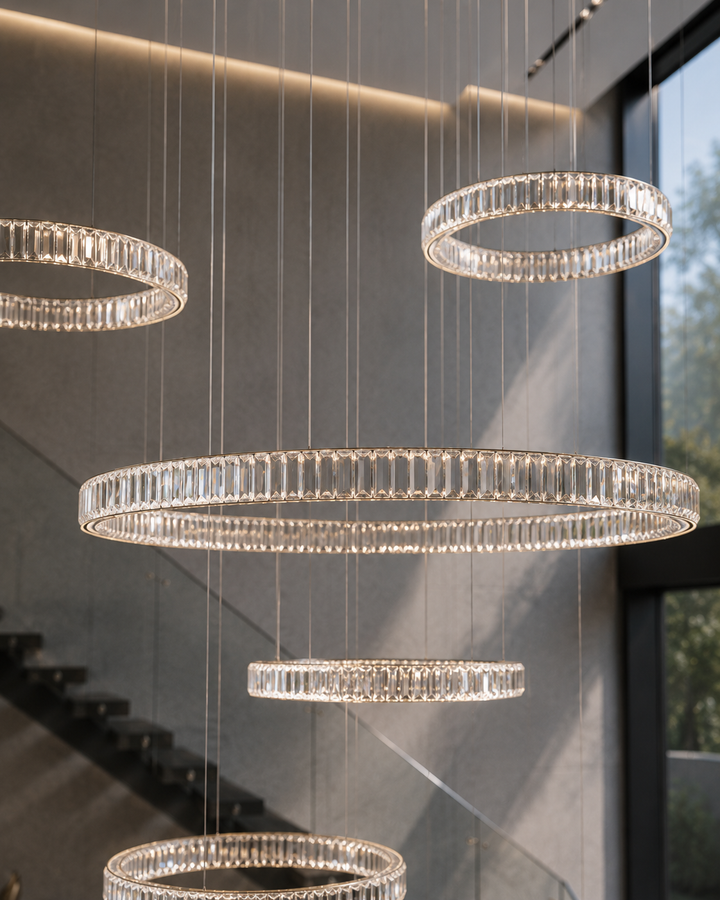 Multi-ring crystal chandelier close-up detail showing precision-cut Krone crystals in a residential staircase void with natural daylight, Pharaoh Chandelier by Lucretia