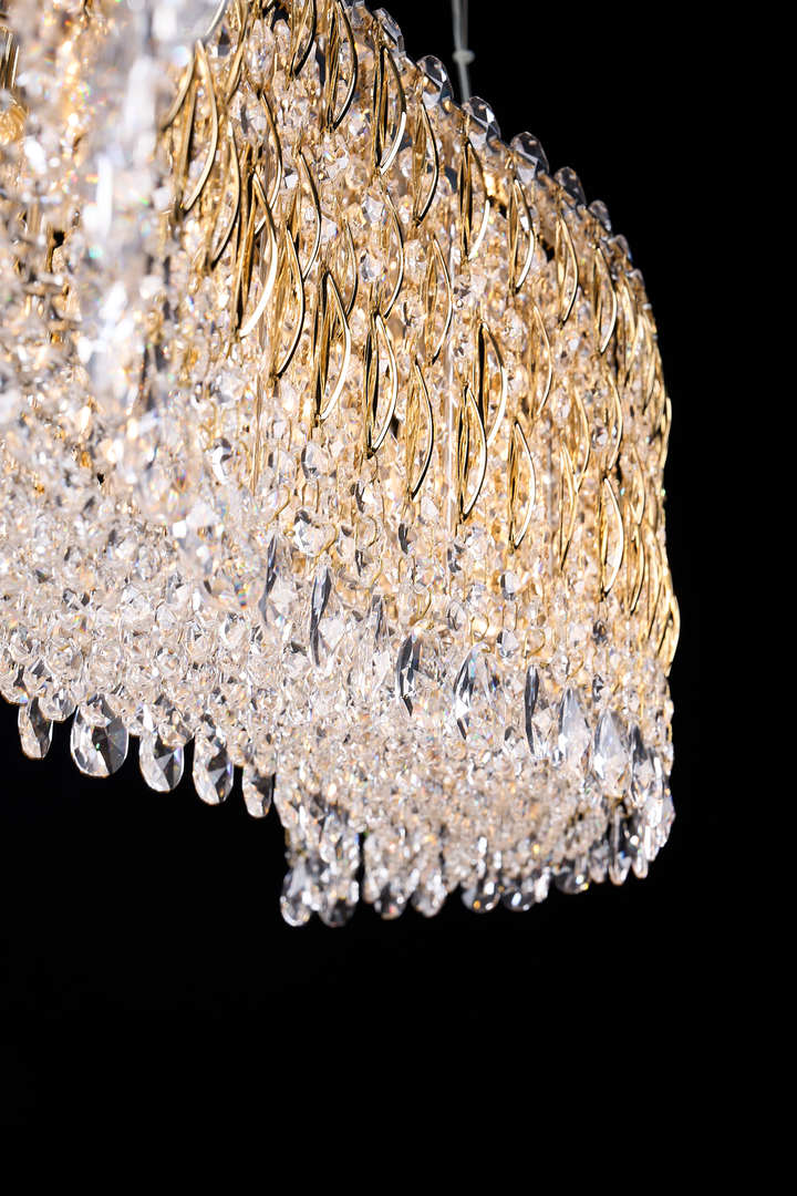 Close-up detail of the Opulent Leaf Linear Chandelier showing gold leaf-shaped accents and cascading clear crystal drops