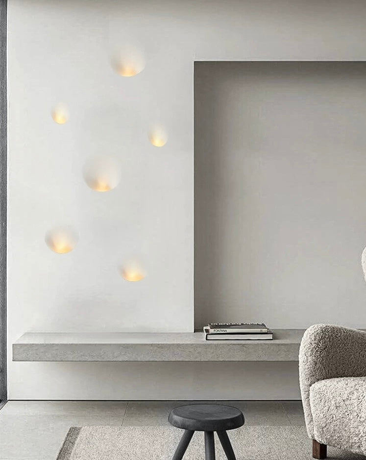 set of oval gypsum wall lights mounted on a white wall creating warm ambient indoor lighting in a contemporary interior