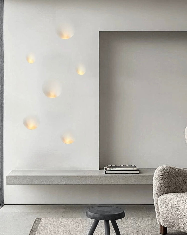 set of oval gypsum wall lights mounted on a white wall creating warm ambient indoor lighting in a contemporary interior