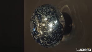 galaxy artistic glass wall lamp shown on a dark wall highlighting its illuminated crater textured surface