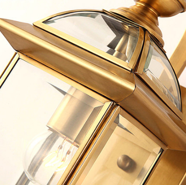 Detail of brass outdoor wall lantern light showing frame and glass texture.