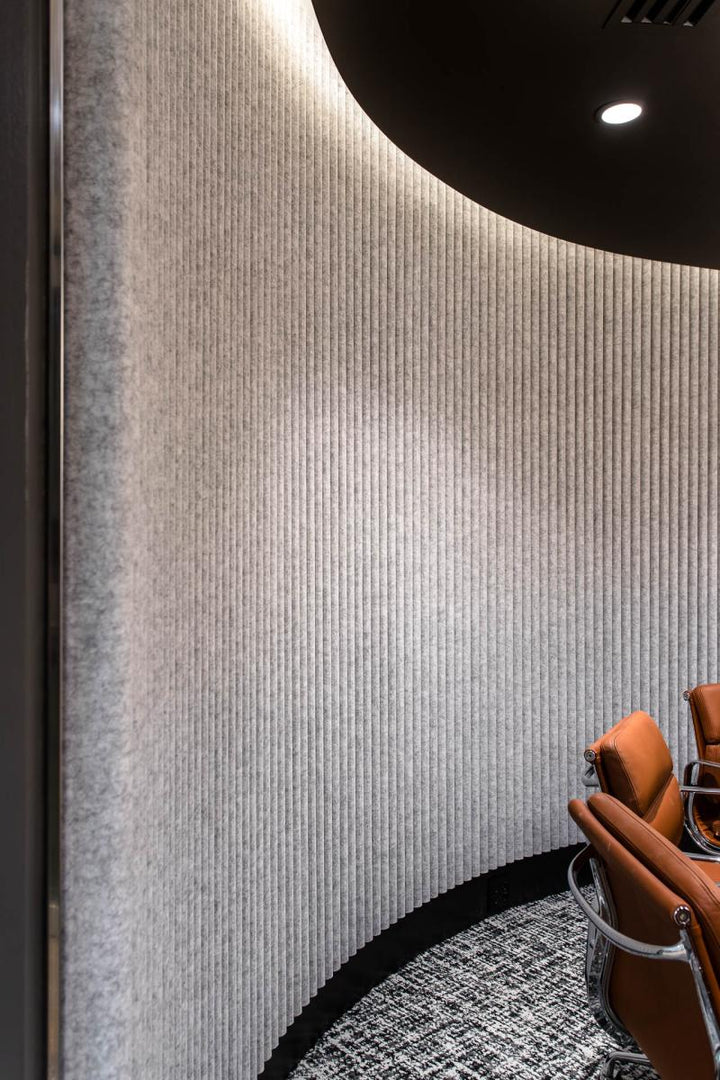 Round line stone architectural wall panels creating a soft textured backdrop in a modern interior space.