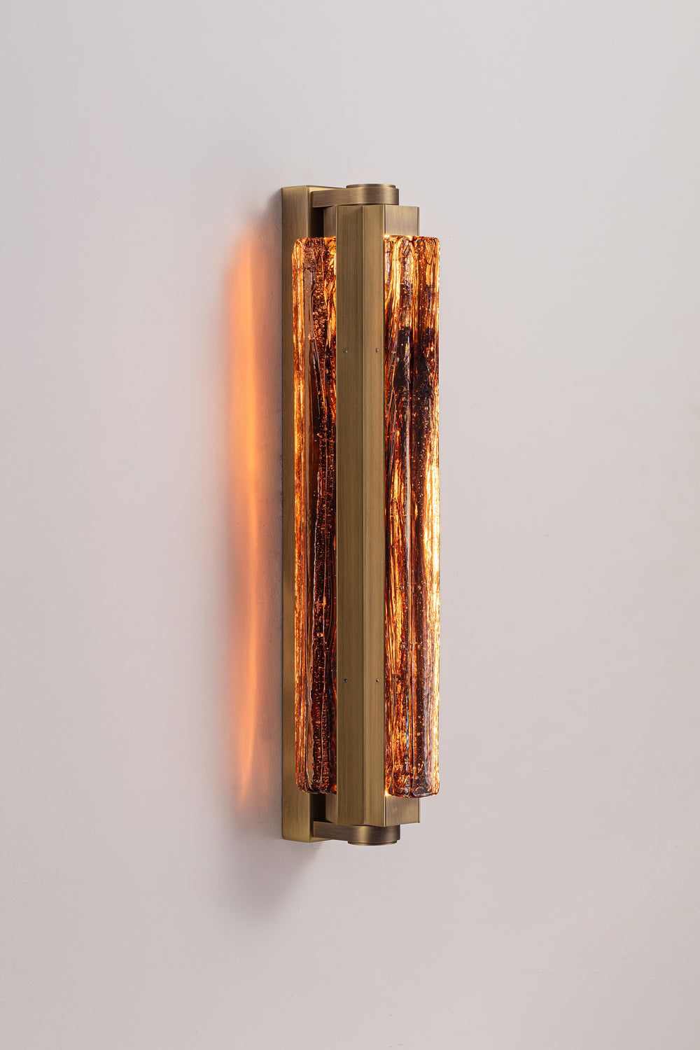 Side view of the Running Water Trio glass wall sconce with warm LED lighting and sculptural antique brass detailing.