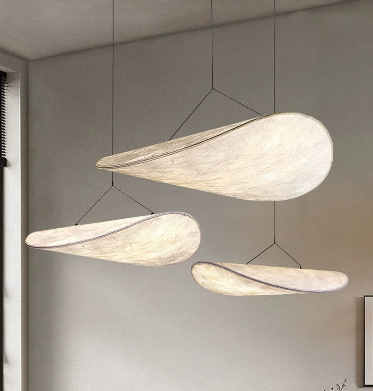 a sculptural pendant light installation suspended in a living space, emitting soft diffused light that creates a calm and atmospheric environment