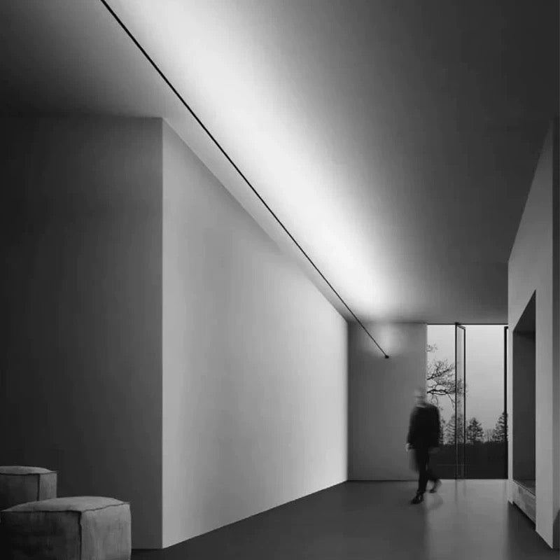 slim linear LED ceiling light creating architectural ambient lighting in a modern monochrome hallway