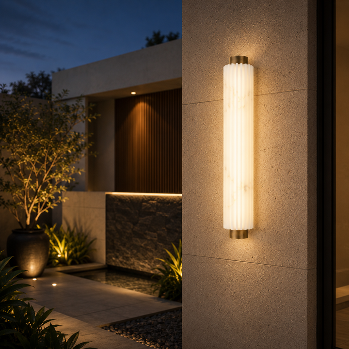 Solid brass faux alabaster outdoor wall light installed on a modern luxury home exterior, featuring a fluted faux alabaster diffuser with warm architectural illumination.