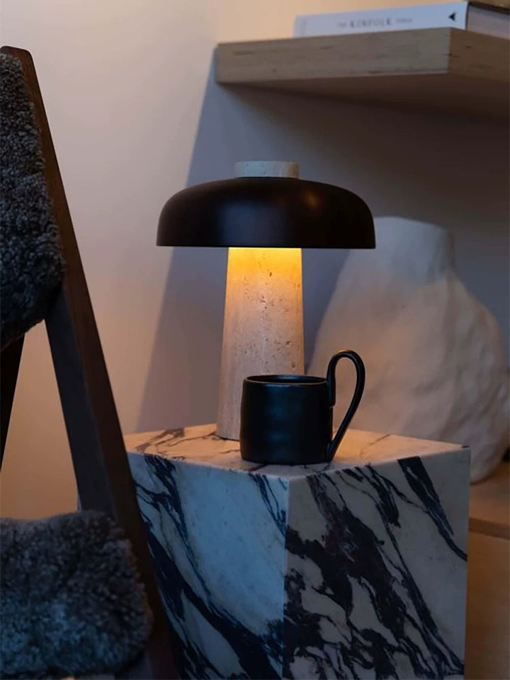Modern stone table lamp with travertine base and black dome shade used as decorative lighting in a stylish living room setting.