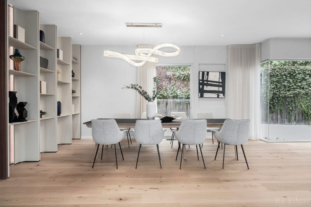 Pharaoh pendant in a horizontal infinity loop above the long dining table, beside curved timber shelving