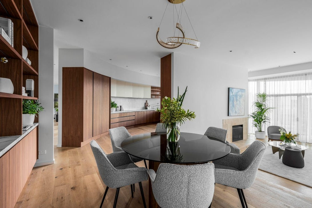 Pharaoh pendant with a gold frame above a round dining table beside the walnut kitchen joinery