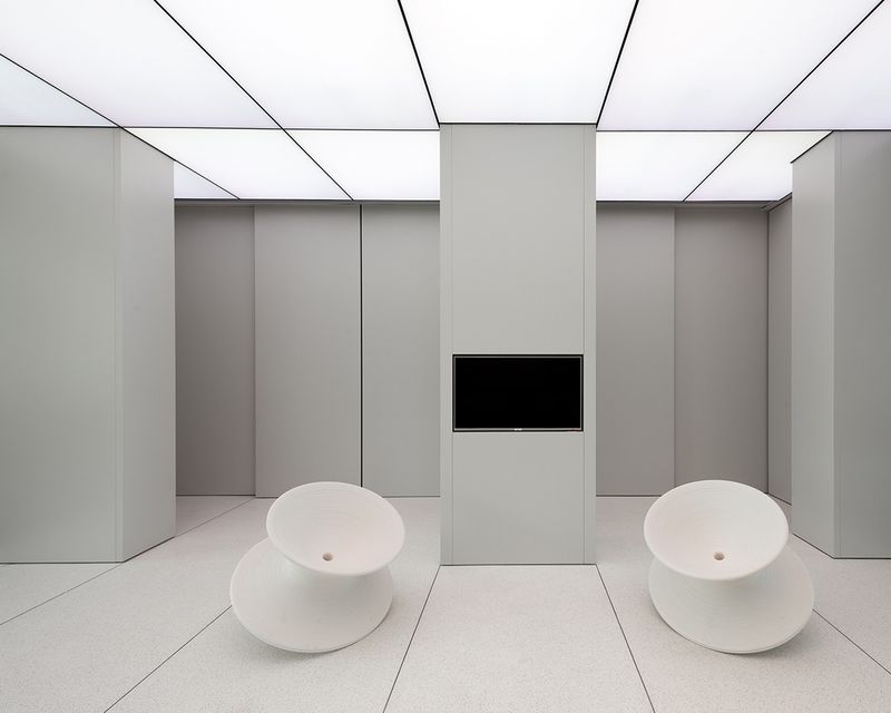 LED stretch ceiling panels illuminating a modern minimalist interior with seamless uniform lighting across walls and ceiling.