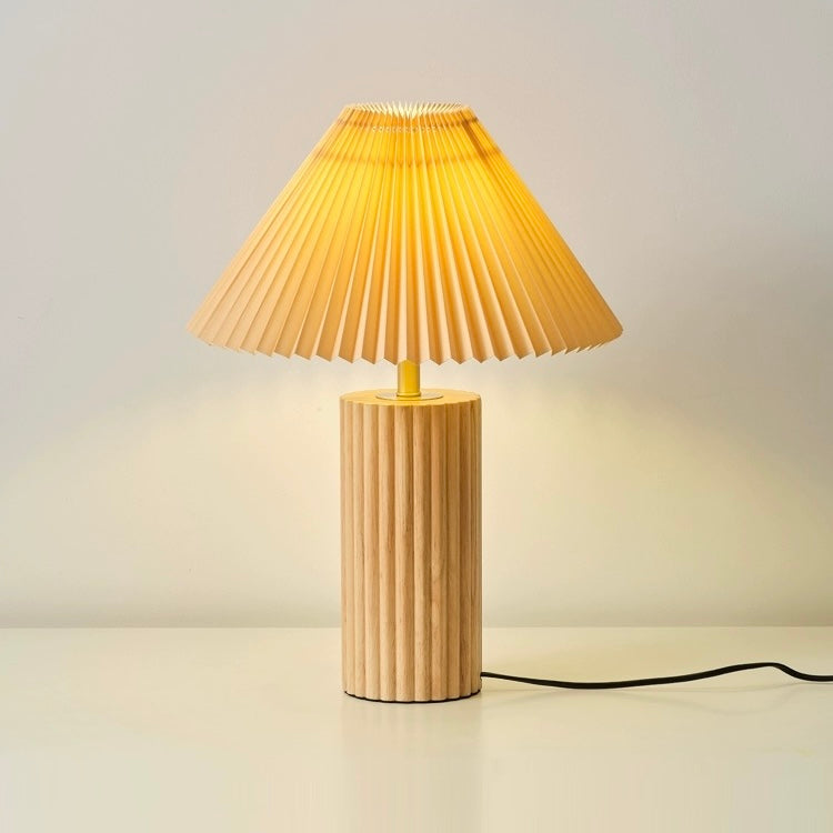 Wooden table lamp with natural solid wood base and pleated fabric shade, offering warm ambient lighting for bedrooms and living rooms.