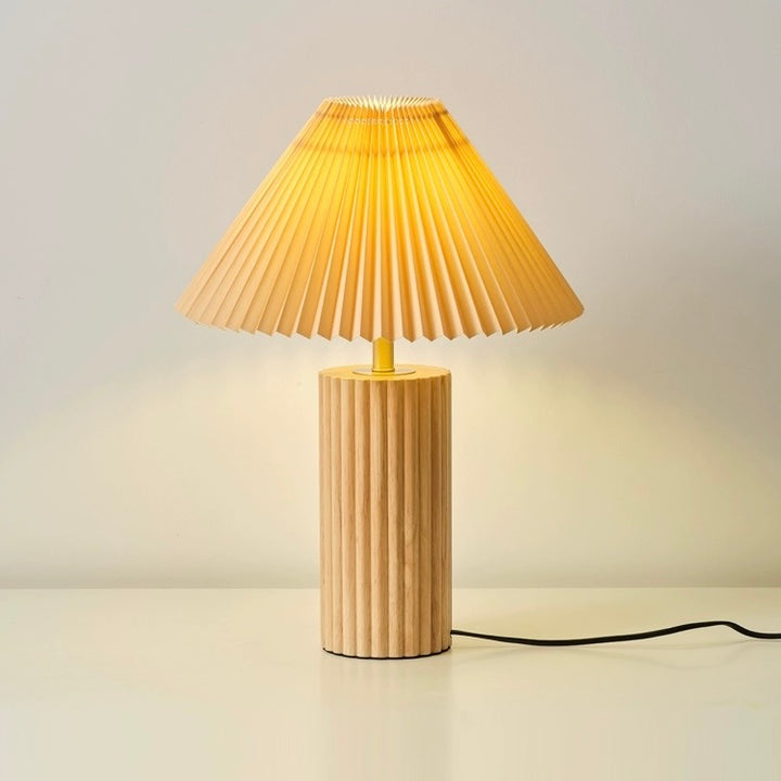 Wooden table lamp with natural solid wood base and pleated fabric shade, offering warm ambient lighting for bedrooms and living rooms.