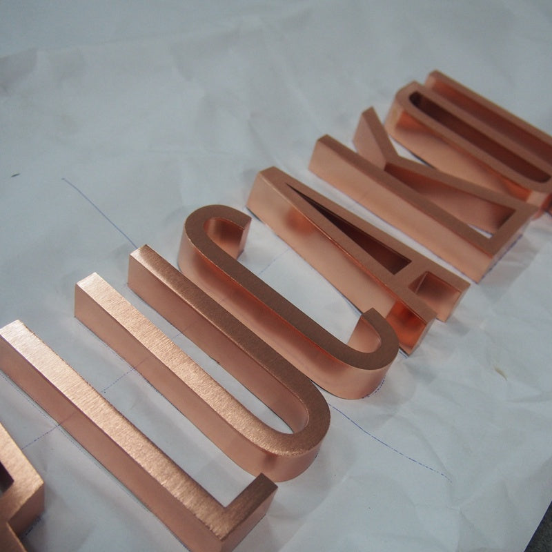 3D stainless steel channel letter sign with rose gold finish, custom fabricated for commercial signage applications.