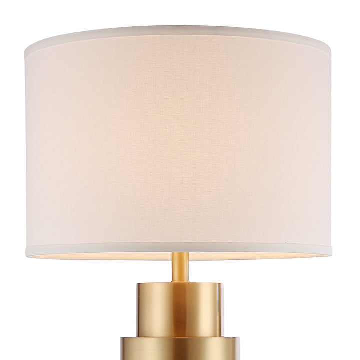 Table lamp with polished brass base and soft fabric shade, creating warm ambient lighting suitable for bedside and living room décor.